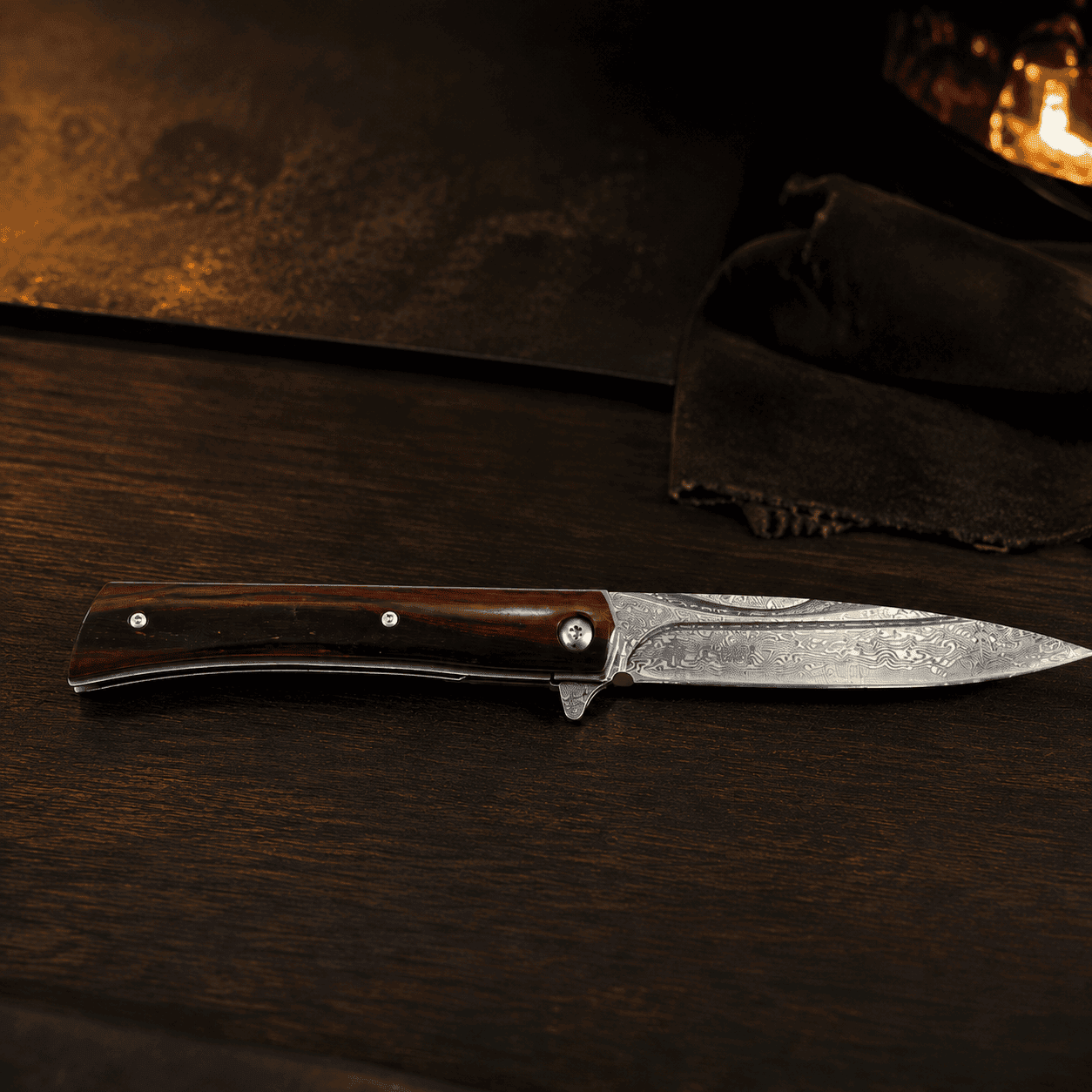 Tosahwi Damascus steel pocket knife with wood handle on a dark walnut workbench