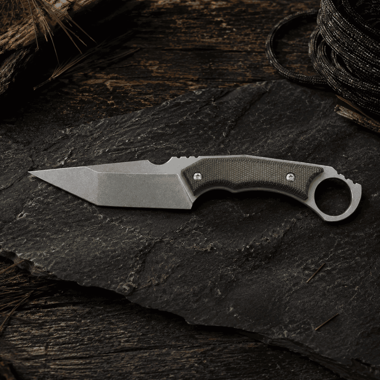 Tosahwi fixed blade hunting knife with green G10 handle on dark outdoor stone